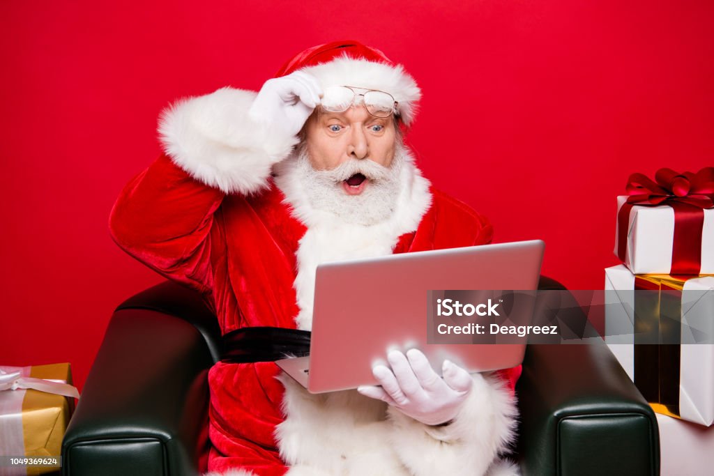 Winter noel december eve christmastime package. Aged mature Santa spectacles open mouth eyes white beard isolated red background look pc wondered astonishment face receive unbelievable email letter Santa Claus Stock Photo