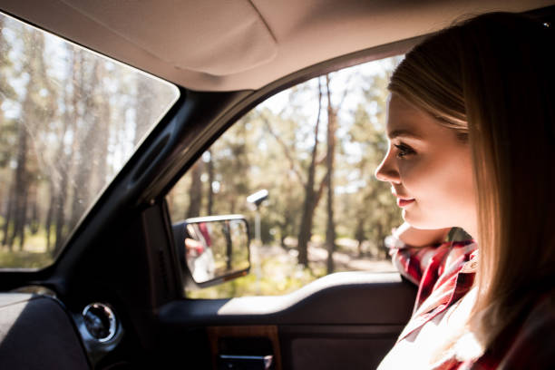 istock beautiful female driver sitting in car in forest 1049376644