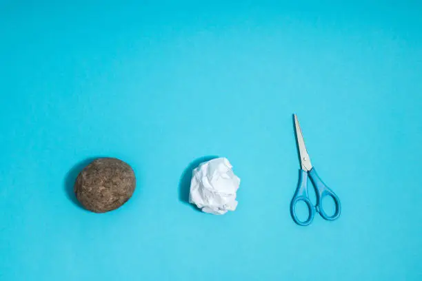 Photo of Rock, paper, scissors concept. Choice, decision making. Top above view on blue background