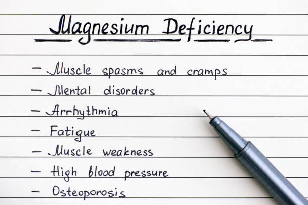 Symptoms of Magnesium Deficiency writing on the list with pen. Symptoms of Magnesium Deficiency writing on the list with pen. Close-up. magnesium deficiency stock pictures, royalty-free photos & images