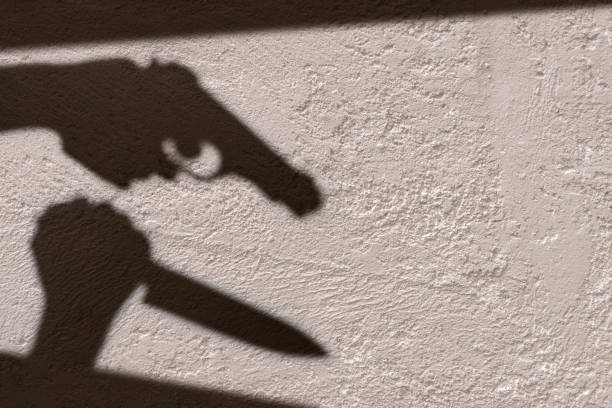 istock A shadow of Hands holding knife and gun. 1049385498
