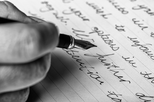 Hand writes words with a fountain pen on paper