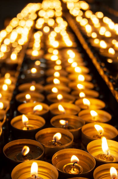 istock Many beautiful lit candles in a row glowing with a golden yellow light - selective focus 1049389146