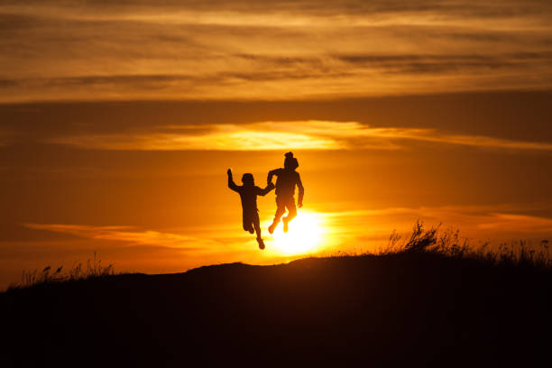 istock Two silhouettes of a child at sunset background 1049389148