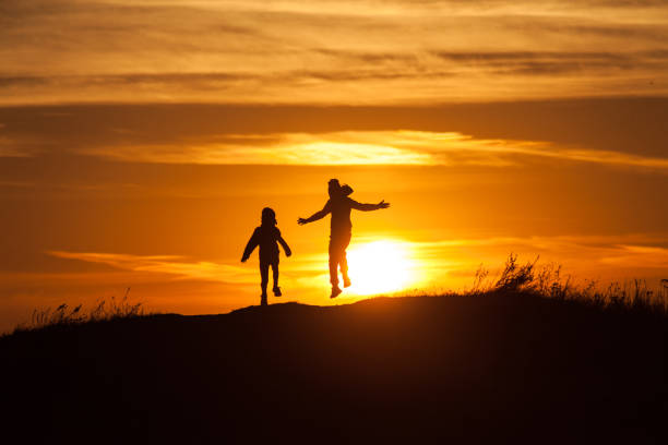istock Two silhouettes of a child at sunset background 1049389366