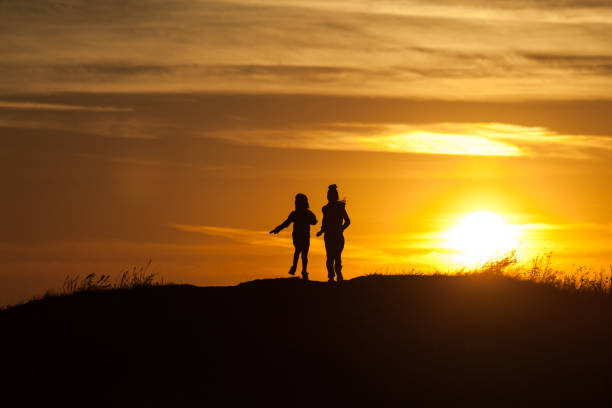istock Two silhouettes of a child at sunset background 1049389456