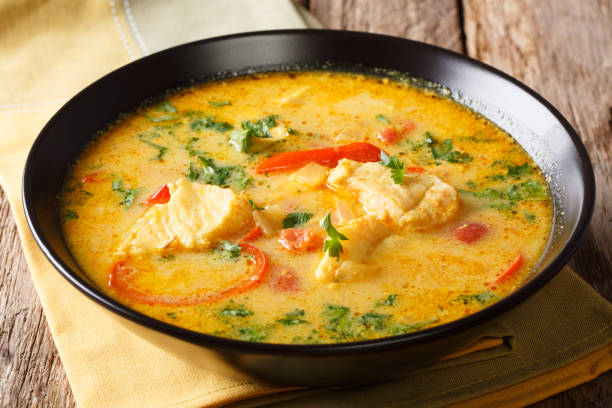 Moqueca stew fish with bell peppers in spicy coconut sauce close-up on a plate. Horizontal Moqueca stew fish with bell peppers in spicy coconut sauce close-up on a plate on a table. Horizontal tropical fish closeup stock pictures, royalty-free photos & images