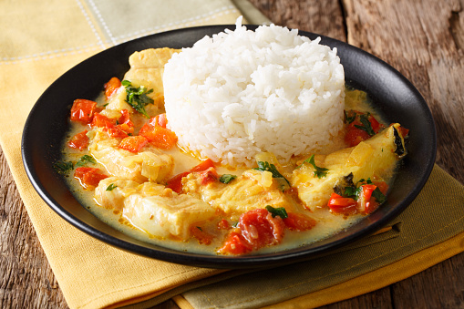 Ecuadorian cuisine: Pescado encocado or fish with coconut sauce close-up on a plate. Horizontal