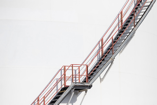 steel ladder on white fuel metal container. white petroleum steel silo with metal stair.