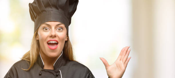 istock Young cook woman happy and surprised cheering expressing wow gesture 1049407590