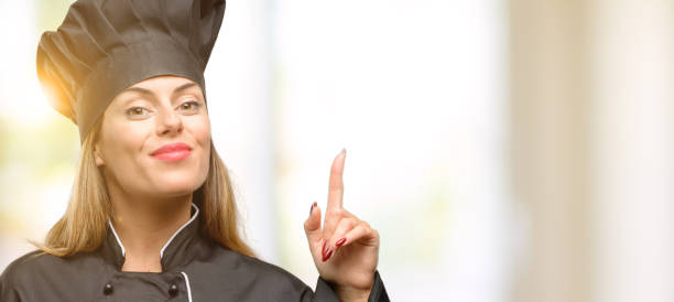 istock Young cook woman happy and surprised cheering expressing wow gesture pointing up 1049407612