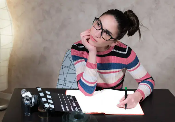 Thoughtful creative scriptwriter woman at desktop while writing