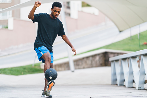 A young man is playing freestyle soccer in a public park.