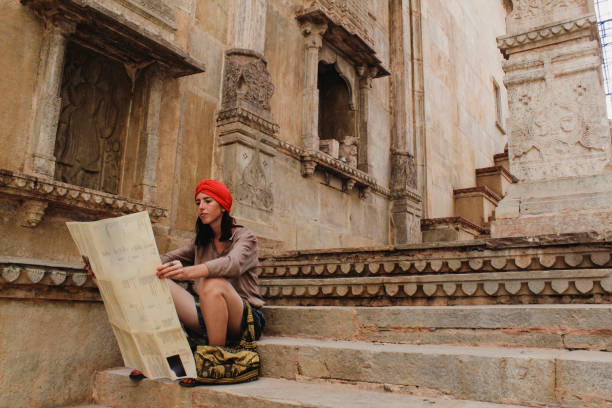 Young Woman Reading Map in Bundi Temple Young traveler is sitting on some steps in Bundi wearing a red turban, looking at a map for directions. jainism photos stock pictures, royalty-free photos & images