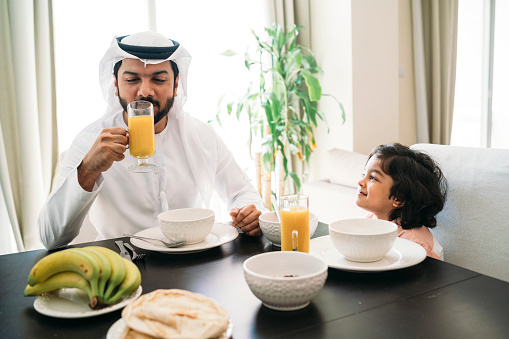 Arab man doing breakfast with his son at home