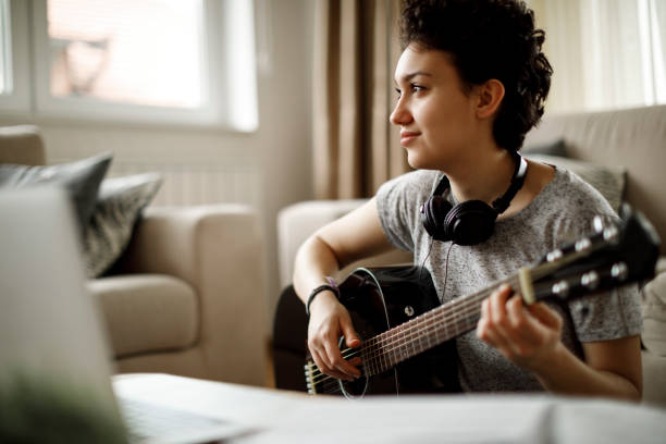istock Smiling girl playing a guitar at home 1049430470