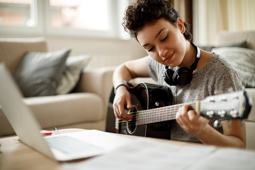 Niña sonriente tocando una guitarra en casa photo