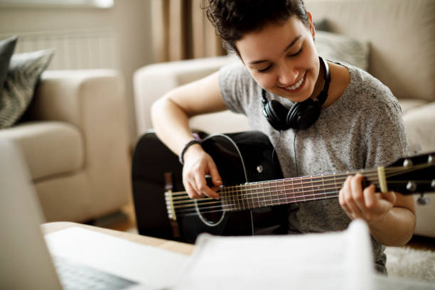 istock Smiling girl playing a guitar at home 1049430658