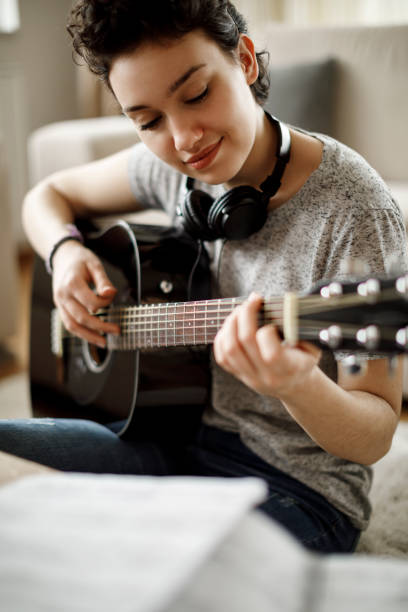 istock Smiling girl playing a guitar at home 1049430670