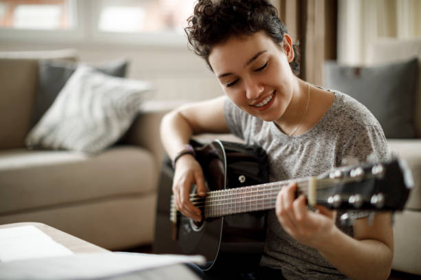 istock Smiling girl playing a guitar at home 1049430680