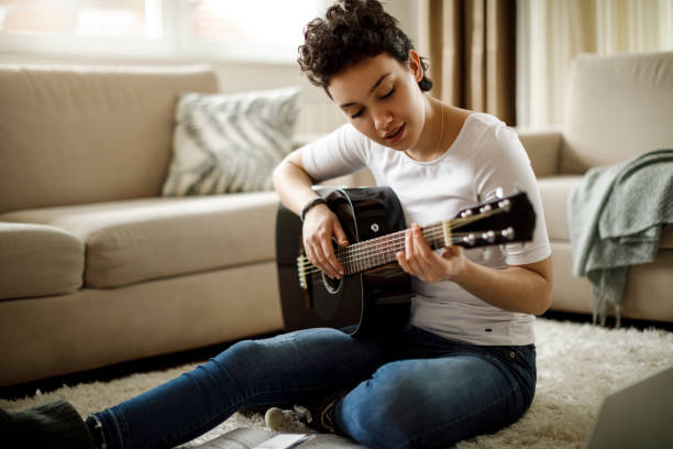 istock Smiling girl playing a guitar at home 1049430724