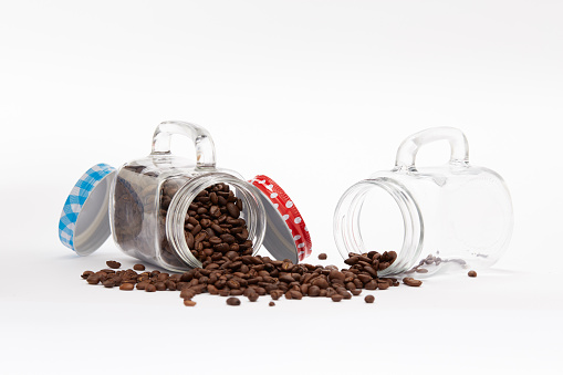 Overturned vintage set of jars full of coffee beans  on a white background with copy space