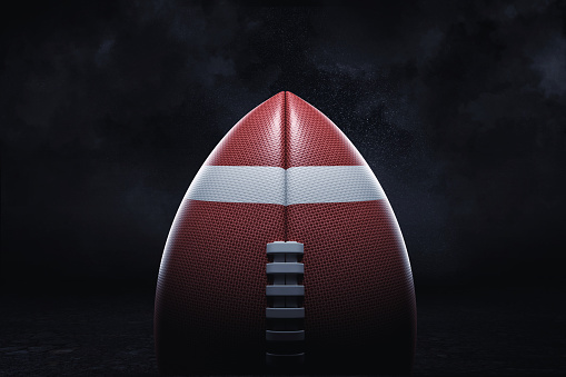 3d rendering of an American football ball with its pointed side up on a dark background. American team game. Contact sport. Sport equipment.