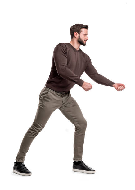 istock A bearded man a casual wear tries to pull an invisible rope with all his force. 1049443416
