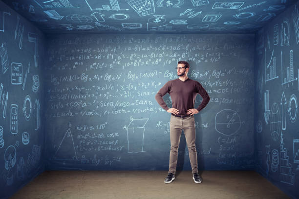 un homme dans des verres se tient dans une petite pièce carrée où les murs sont recouverts de craie équations et graphiques. - formula blackboard complexity scientist photos et images de collection