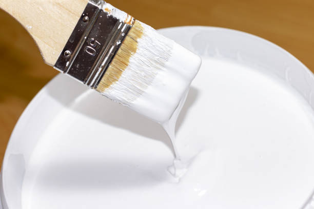 istock White paint flowing down from the brush into a bucket with paint 1049447292