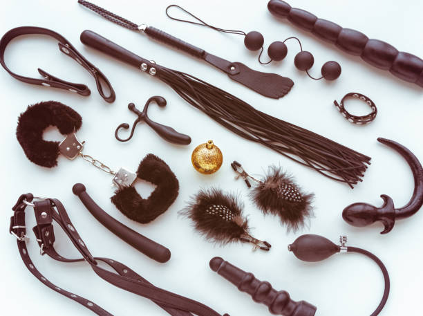 Various sex toys (whip, dildo, handcuffs, butt plug, anal balls and other) and a golden christmas ball. stock photo