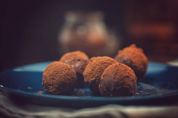 Delicious homemade chocolate truffles sprinkled with cocoa powder on dark background
