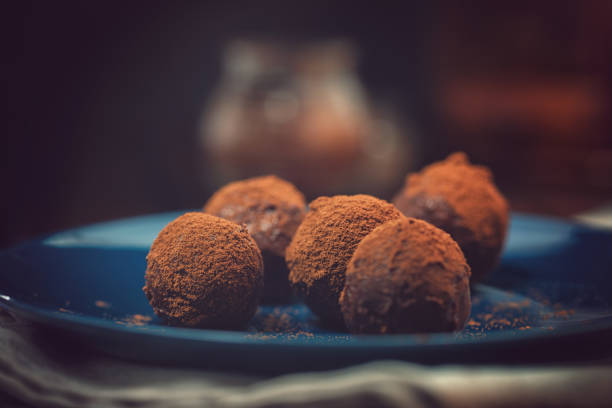 Delicious Homemade Chocolate Truffles Delicious homemade chocolate truffles sprinkled with cocoa powder on dark background chocolate truffle making stock pictures, royalty-free photos & images