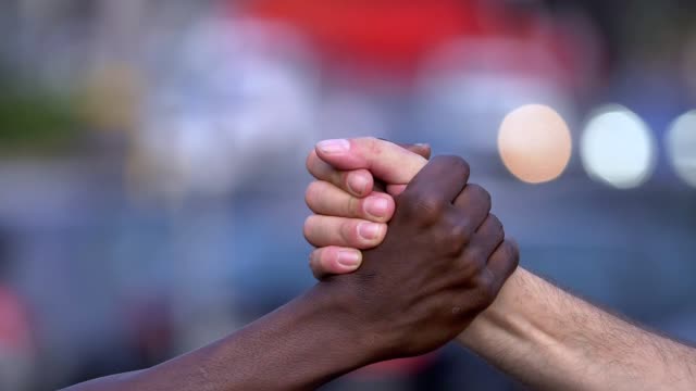 close up on friendship, interracial, brotherhood. Black and white man hand shake