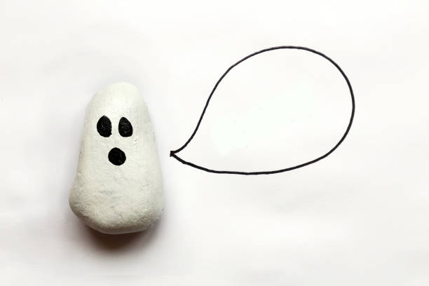 A cartoon painted Halloween Ghost rock is isolated on a white background with a speech bubble that is empty.