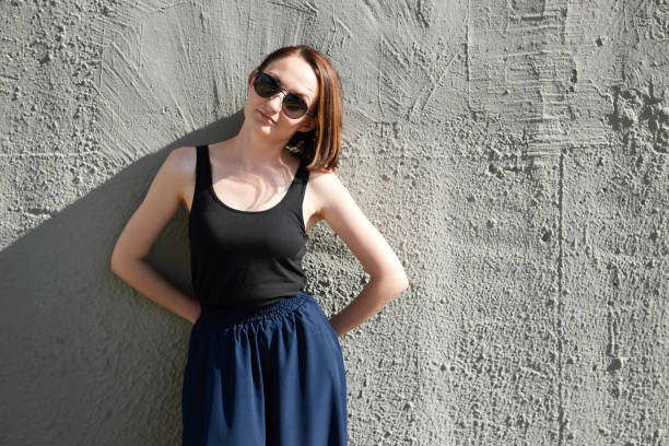 istock young girl posing against a concrete wall, dressed in black, hard light and shadows 1049472114
