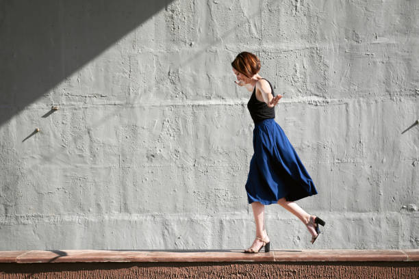istock young girl posing against a concrete wall, dressed in black, hard light and shadows 1049472128