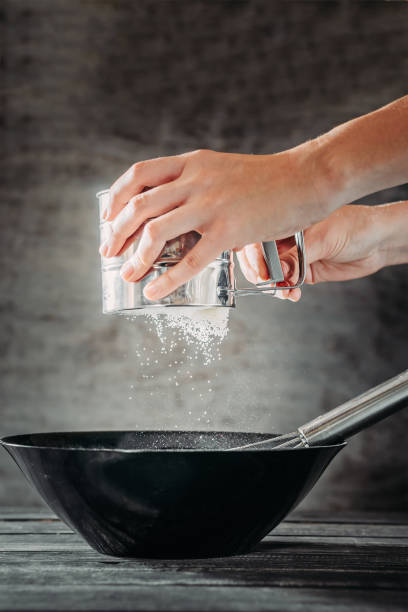 istock woma's hands sift flour over bowl with whisk on dark background 1049472668