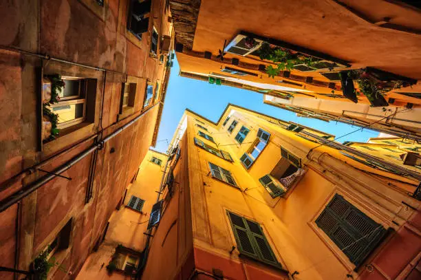 Looking upward a narrow street with traditional yellow houses in Genoa, Italy