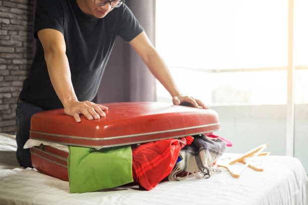 istock Midsection Of Man Packing Suitcase On Bed At Home 1049476464