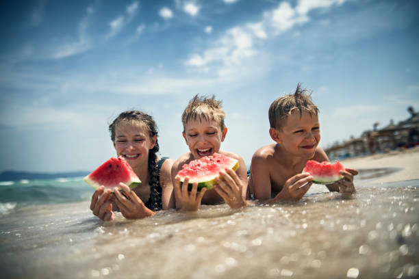 glückliche kinder essen wassermelone am strand - spanisches essen stock-fotos und bilder