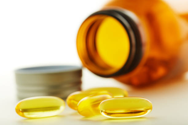 Brown glass pill bottle with some pills inside on white background