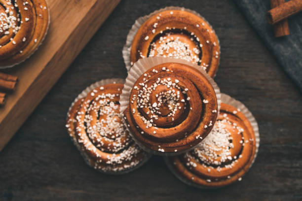 Traditional Swedish cinnamon bun on a wooden table Top down view of traditional Swedish cinnamon roll. Typical dessert in Sweden, especially for Cinnamon Bun Day. kanelbulle stock pictures, royalty-free photos & images