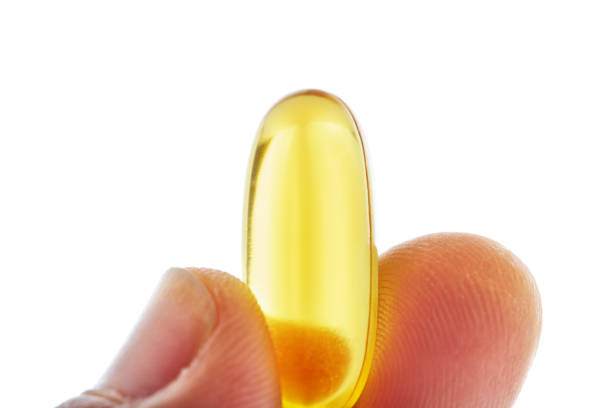 Hand holding fish oil suplement Omega 3 capsule
