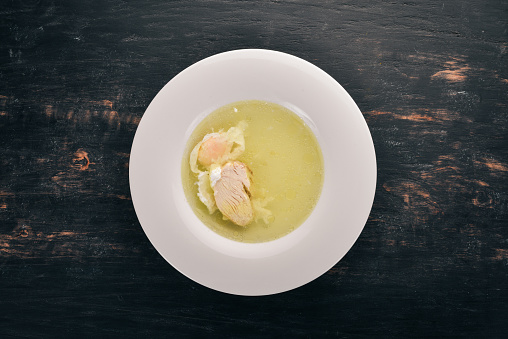 Chicken soup with egg. On the old wooden background. Free space for text. Top view.
