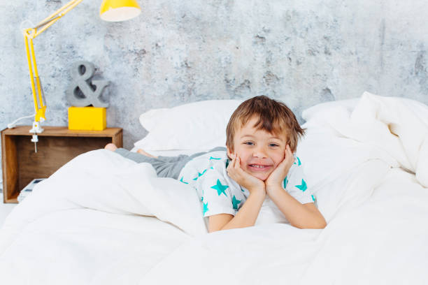 istock Portrait Of Smiling Boy Lying On Bed 1049494732