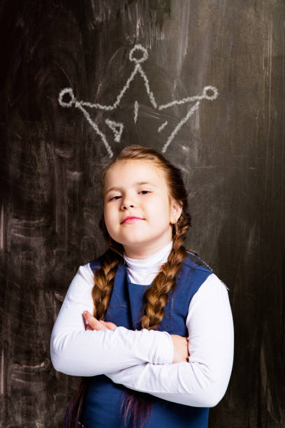 istock schoolgirl against chalkboard, with drawn crown 1049494742