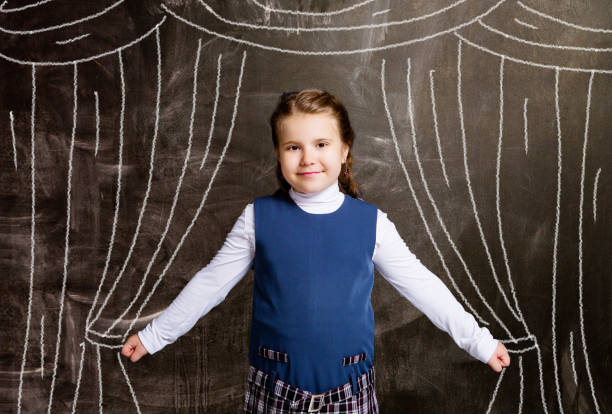 schoolgirl against chalkboard, with drawn curtains stock photo