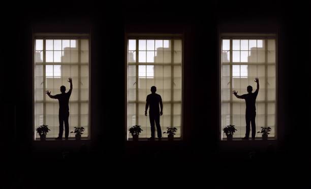 istock Multiple Image Of Silhouette Man Standing On Window Sill 1049498398