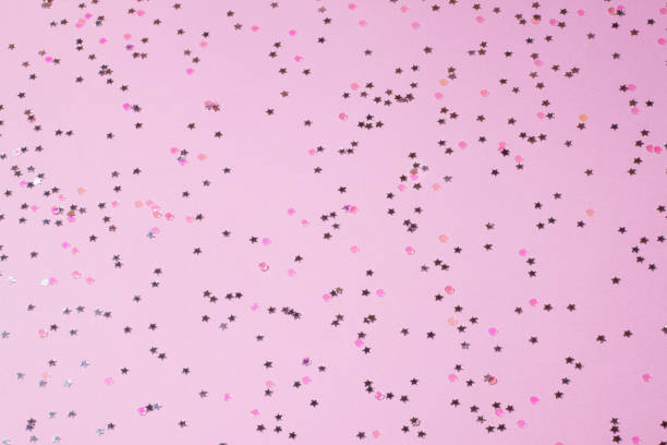 istock Pink sequins on a pink pastel background with confetti as asterisks. 1049498506